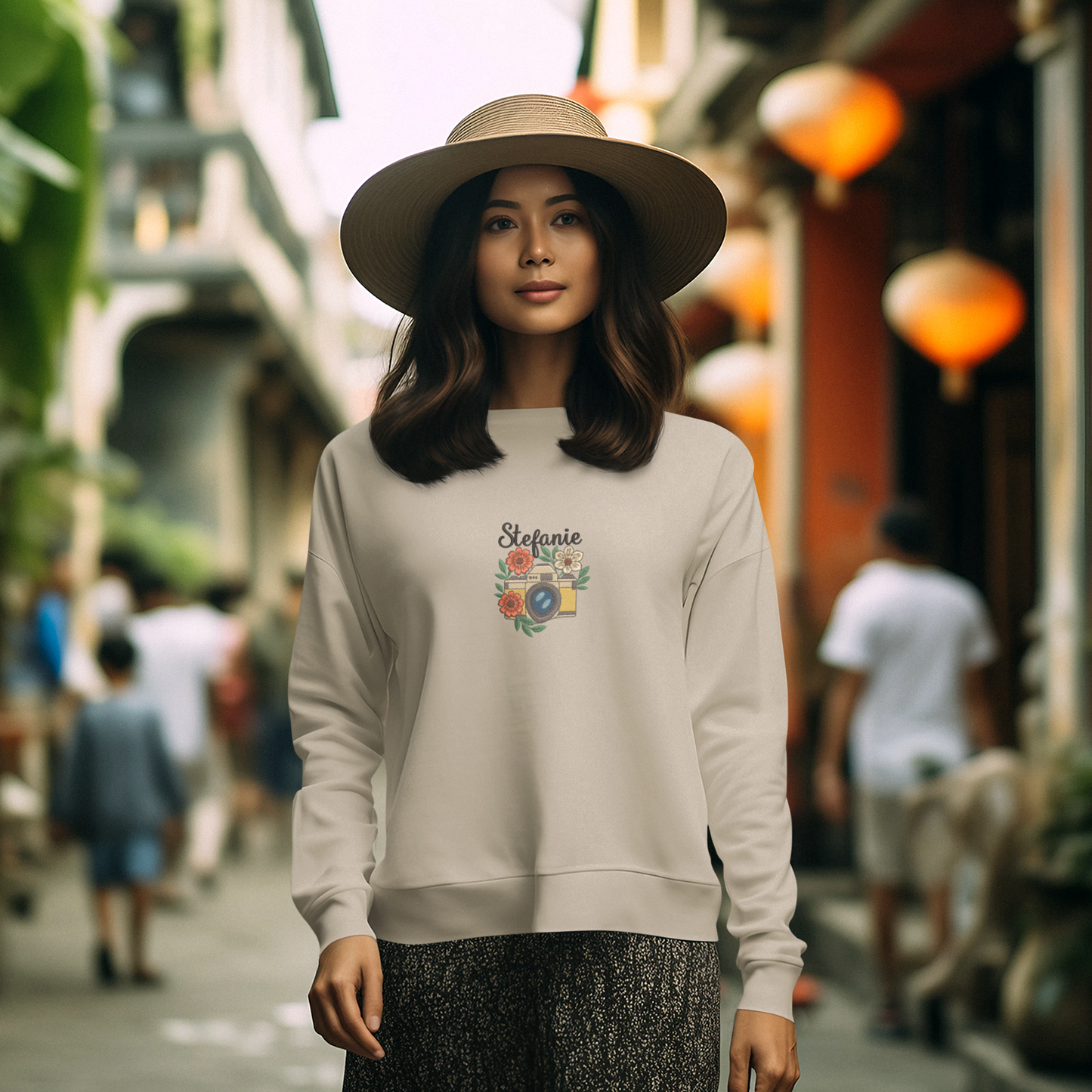 Frau trägt ein sand Sweatshirt mit besticktem Kamera- und Blumenmotiv sowie personalisiertem Namen Stefanie.