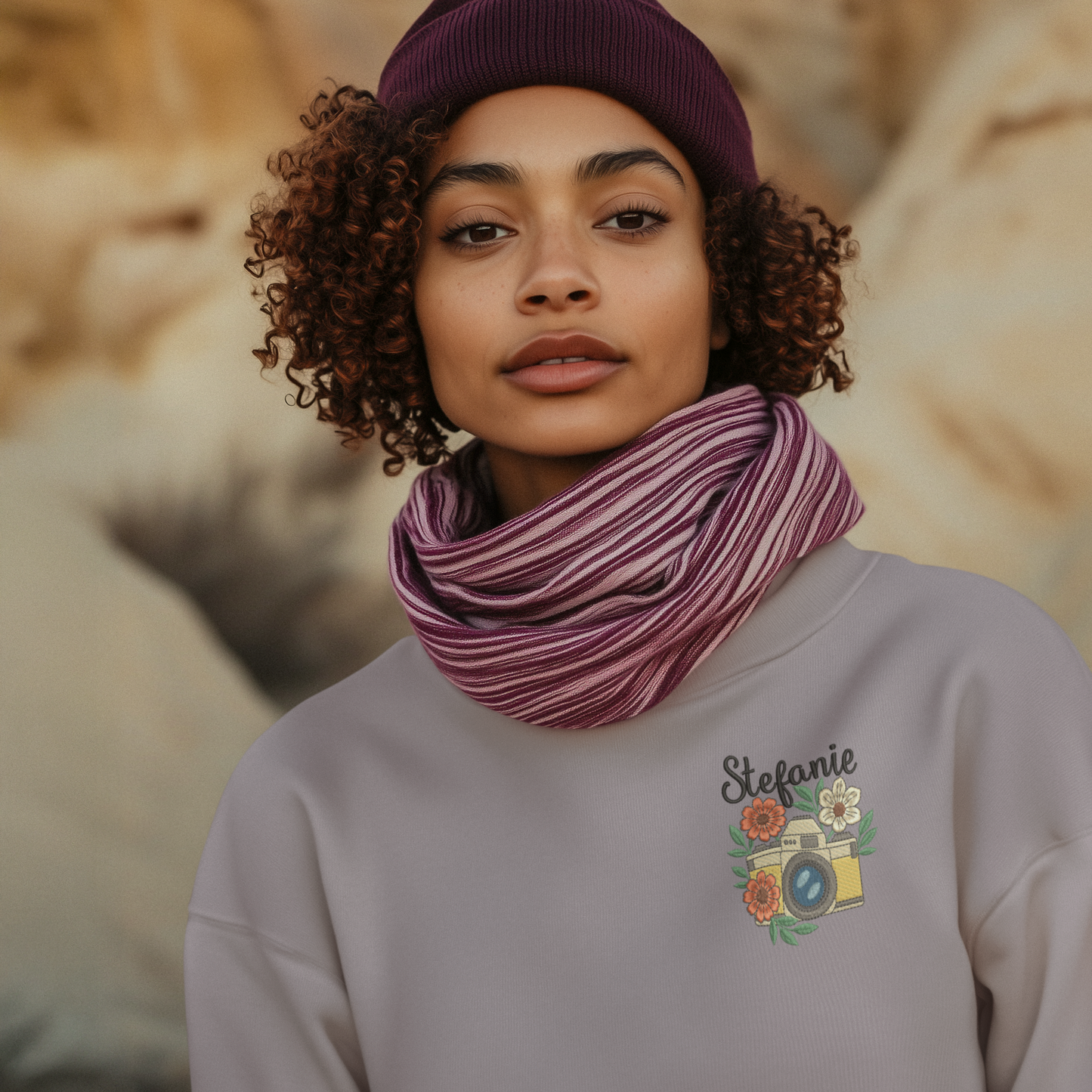 Frau trägt ein lila Sweatshirt mit besticktem Kamera- und Blumenmotiv sowie personalisiertem Namen Stefanie.