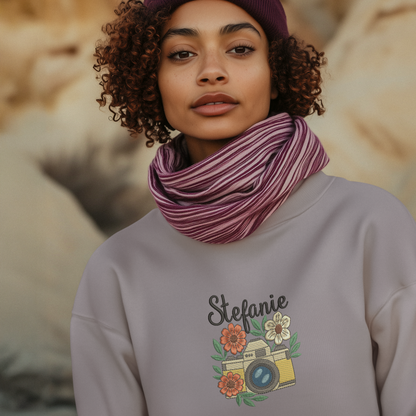 Frau trägt ein lila Sweatshirt mit besticktem Kamera- und Blumenmotiv sowie personalisiertem Namen Stefanie.