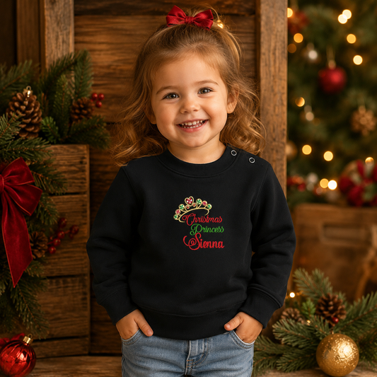Mädchen in einem schwarzen Kinder-Sweatshirt mit bunter Weihnachts-Stickerei ‚Christmas Princess und Krone, festliches Outfit für Mädchen, personalisiert
