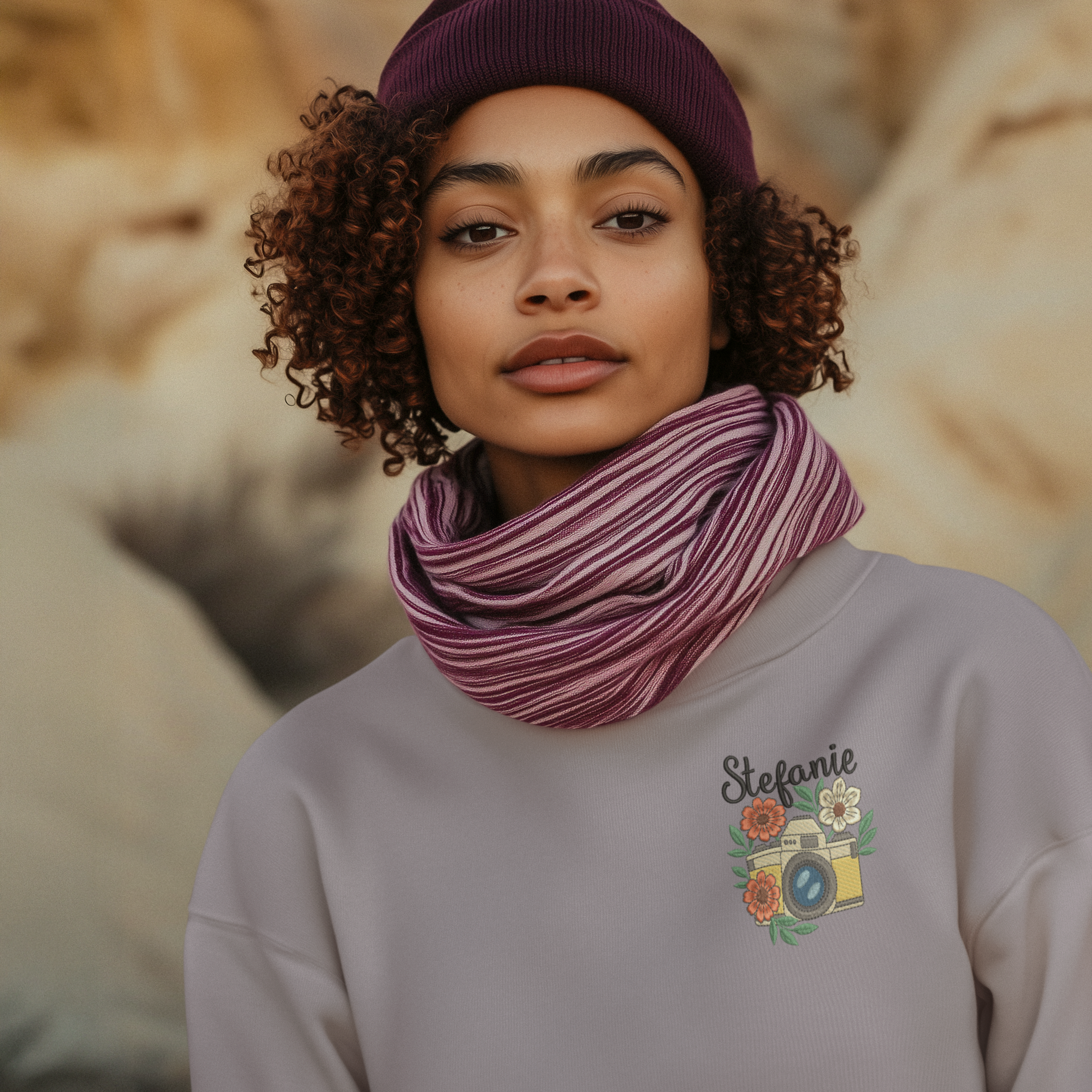 Frau trägt ein lila Sweatshirt mit besticktem Kamera- und Blumenmotiv sowie personalisiertem Namen Stefanie.